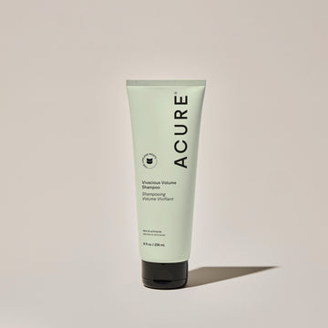 A tube of ACURE volumizing shampoo for fine hair, with a mint green label, against a neutral background.